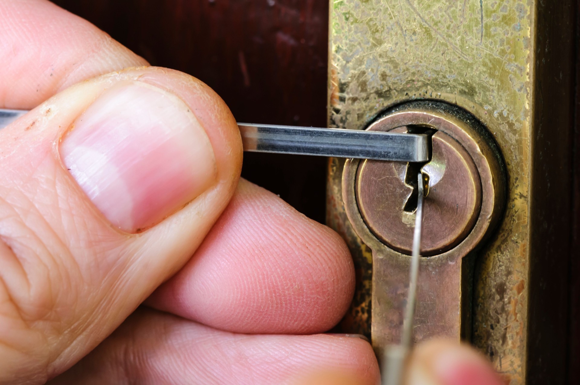 A man uses lockpicking tools to pick the lock of a house.